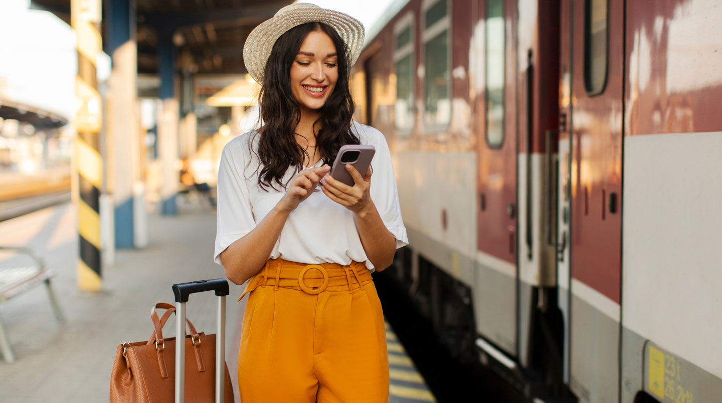 Primo piano di una mano che tiene uno smartphone con app di viaggio aperta mostrando una mappa sfocata, sfondo morbido