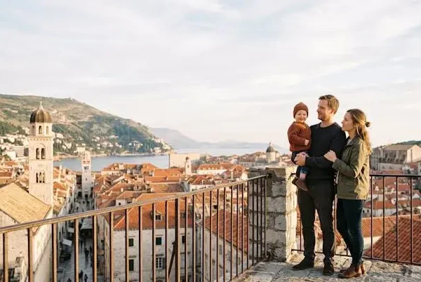 Genitori e bambino osservano il panorama di una destinazione di vacanza europea, simbolo di serenità e pianificazione familiare